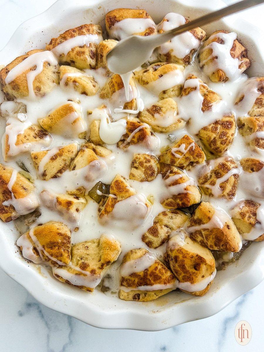 Drizzling cinnamon rolls with icing.