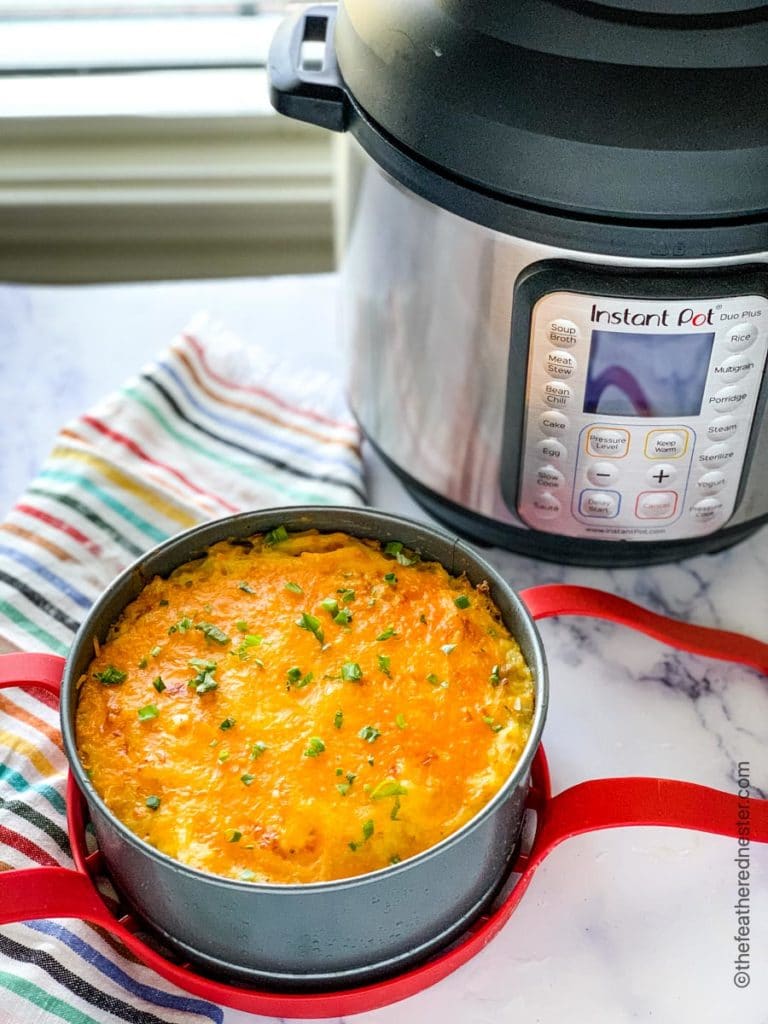 A pan of this copycat version of Cracker Barrel's hash brown casserole on a red silicone sling with an instant pot in the background