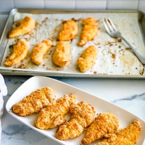 a platter of bisquick chicken tenders with a baking sheet of them in the background.