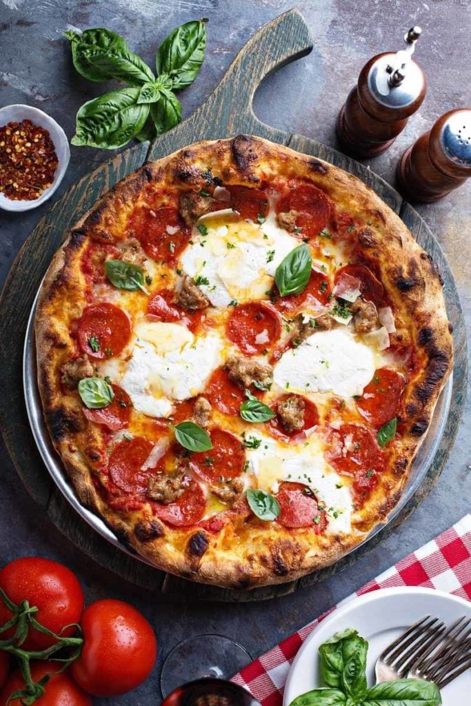 pizza crust with salad, spices, and tomatoes