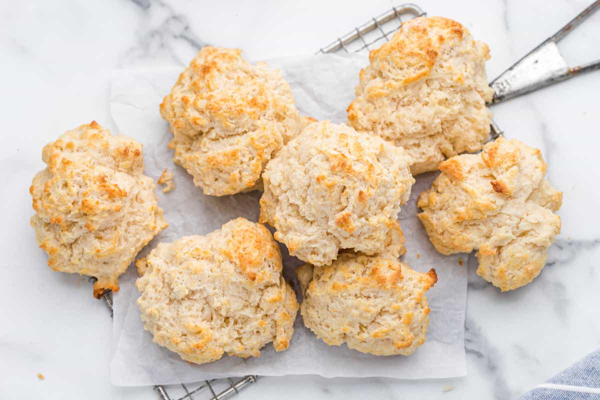 A batch of drop biscuits on a strainer with parchment paper