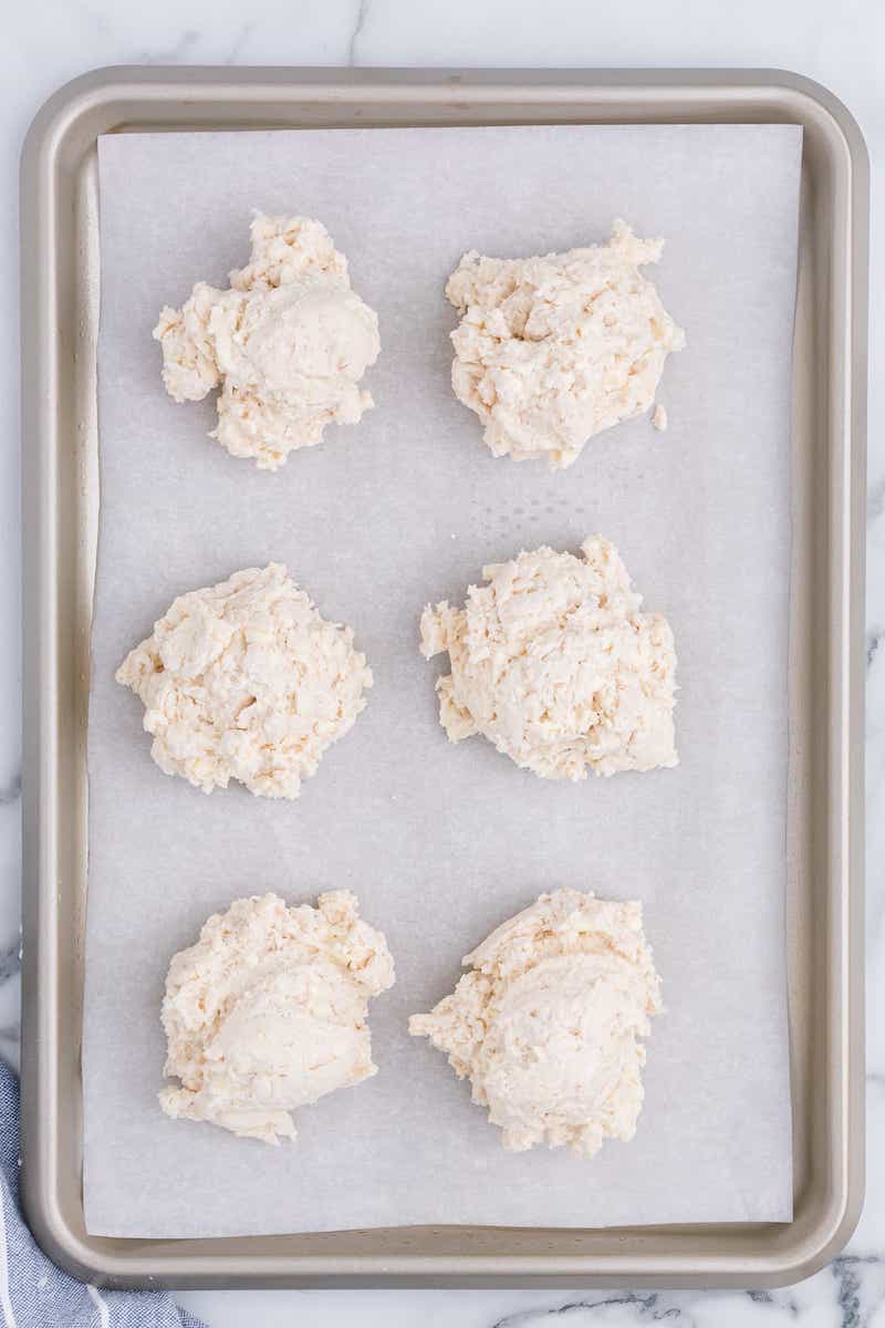 unbaked drop biscuits on a parchment lined baking sheet.