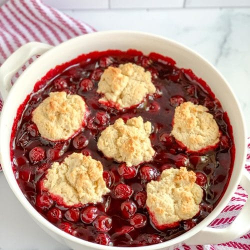 a white casserole dish of Bisquick cherry cobbler with cherry pie filling.