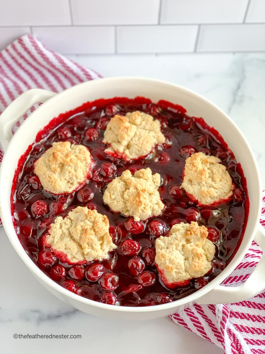 a white casserole dish of Bisquick cherry cobbler with cherry pie filling.