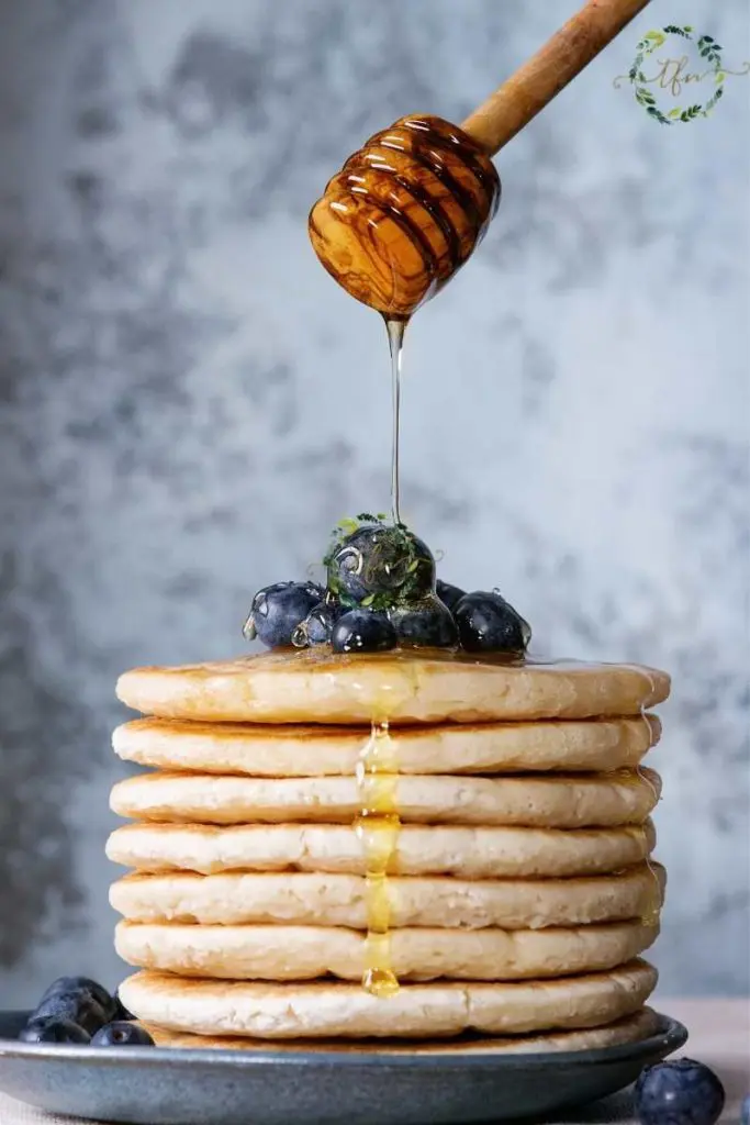 drizzling honey over a stack of Bisquick hotcakes and blueberries