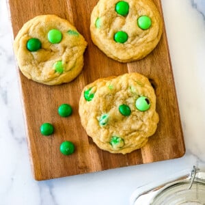 green m and m cookies on a wooden serving board