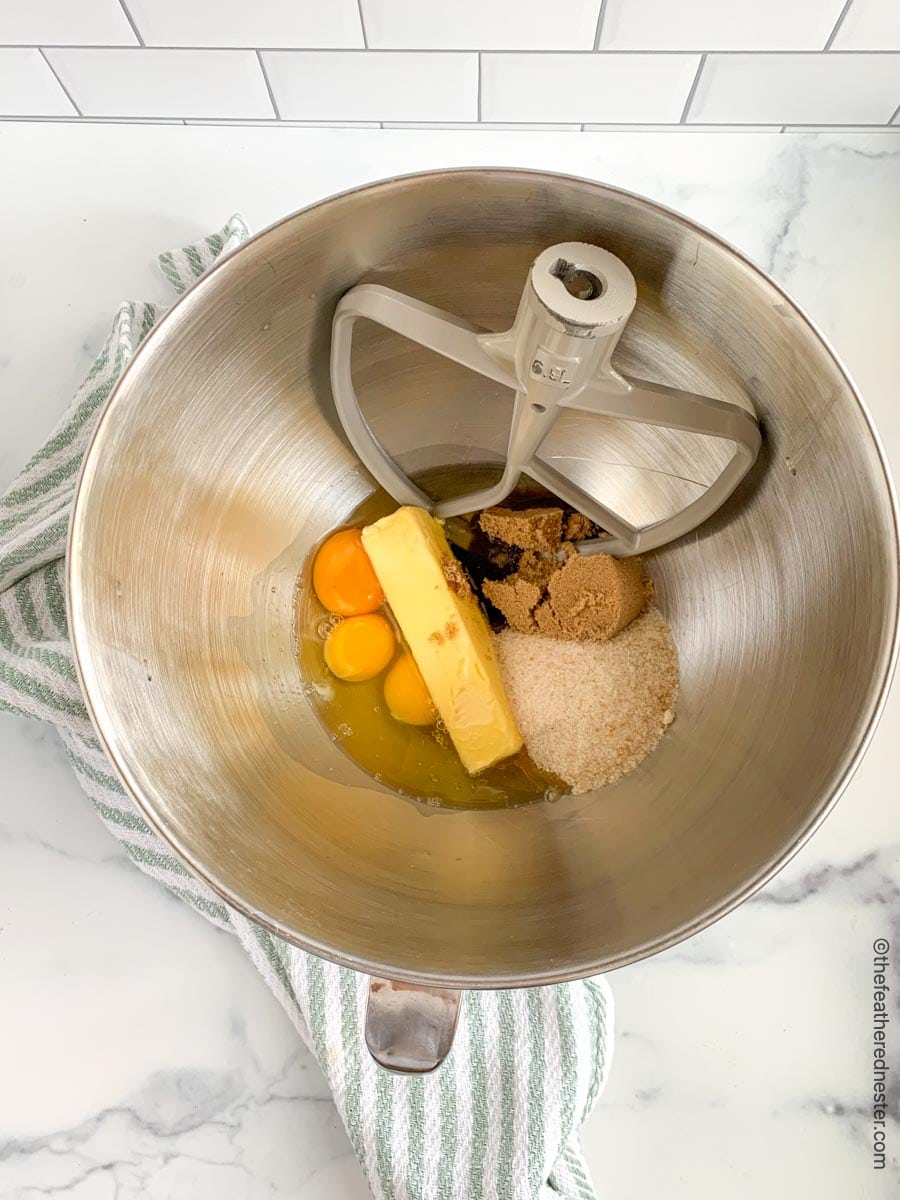 Mixing bowl filled with butter, eggs, brown sugar and white sugar.