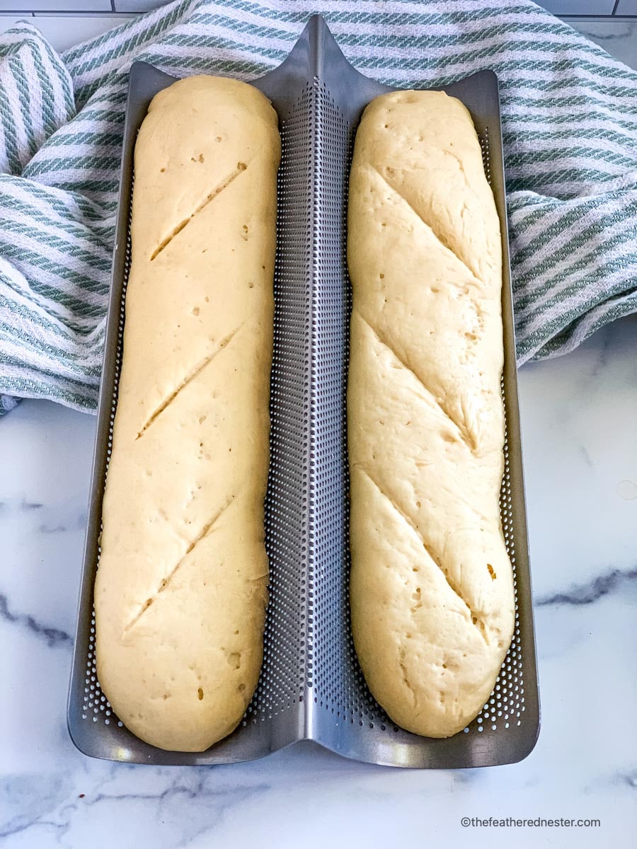Two pans of French bread rising in a French bread pan.