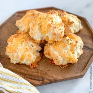 a wooden platter of cheddar bay biscuits.