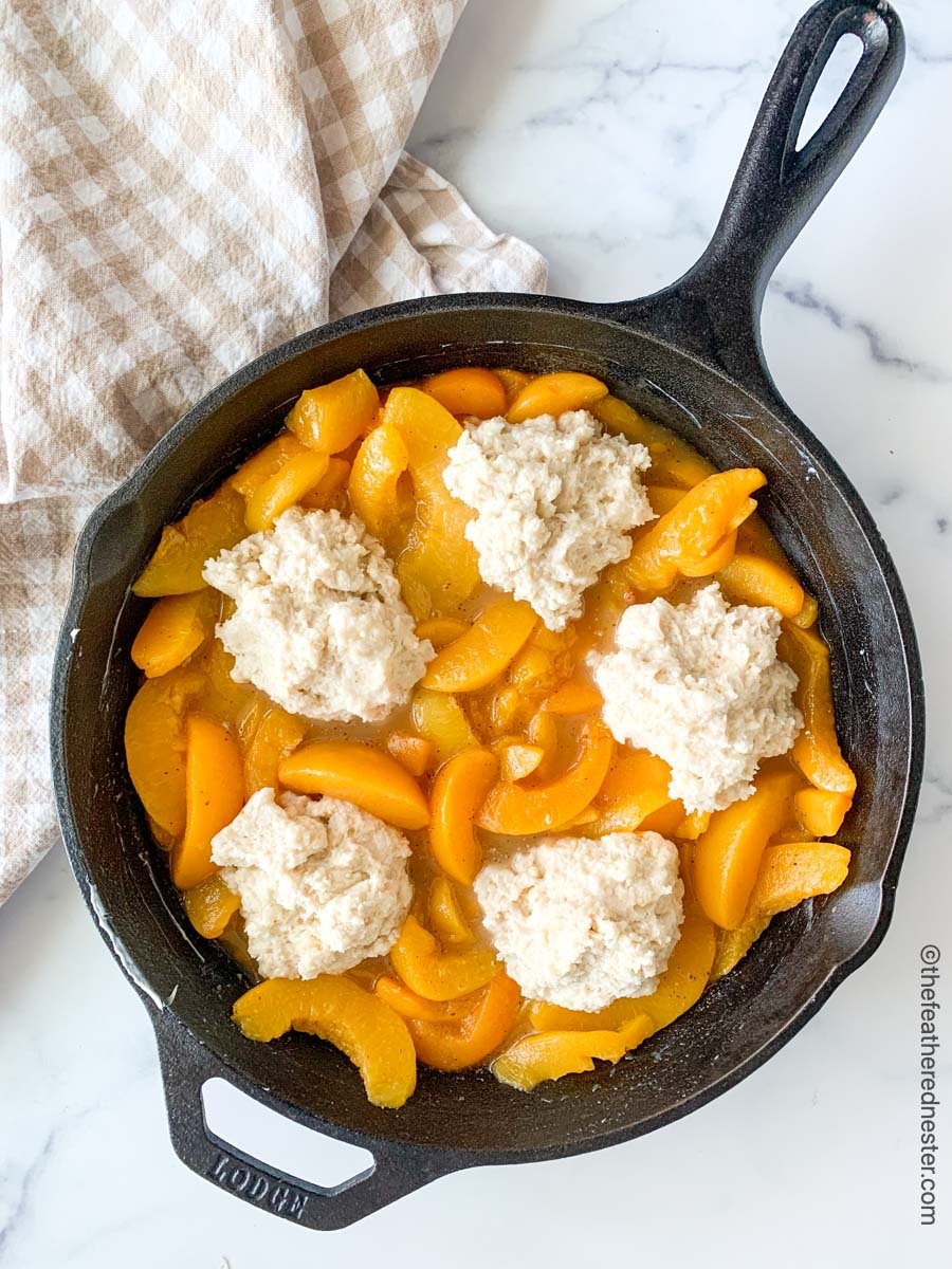 Prepared peach cobbler in a cast iron before it bakes.