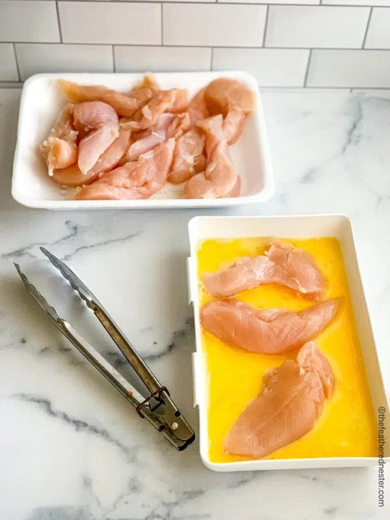 two trays of raw strips of poultry; one tray has beaten egg in it.