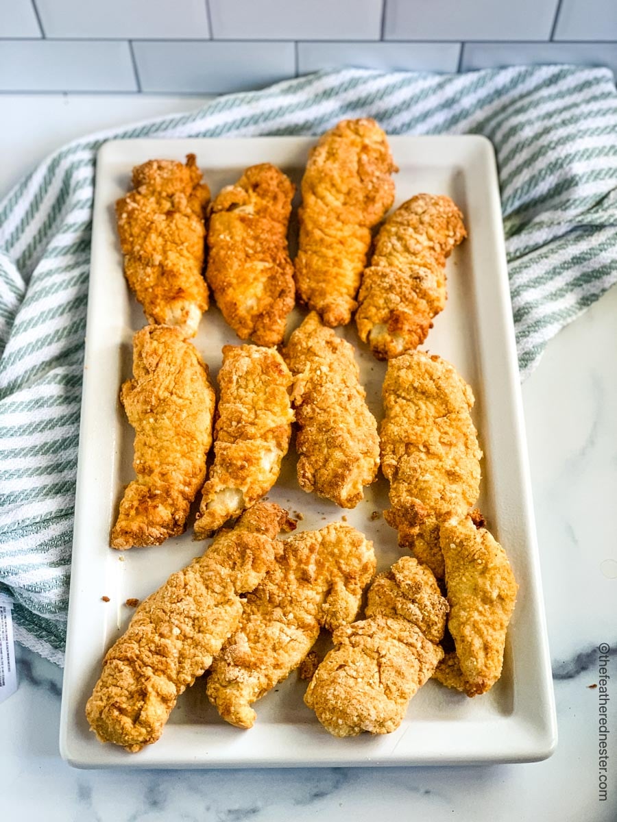 chicken tenderloins on a white platter over a green and white napkin