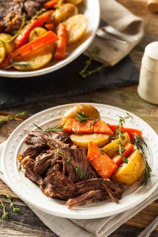 plate of crock-pot pot roast with a serving bowl in the background