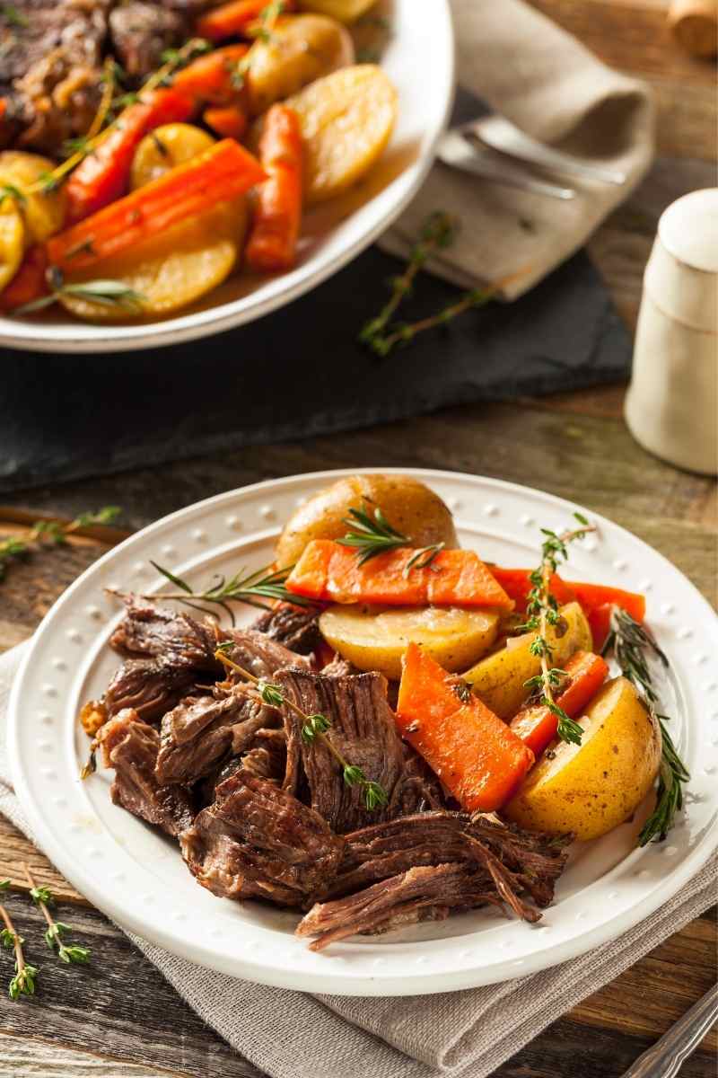 plate of crock-pot pot roast with a serving bowl in the background.