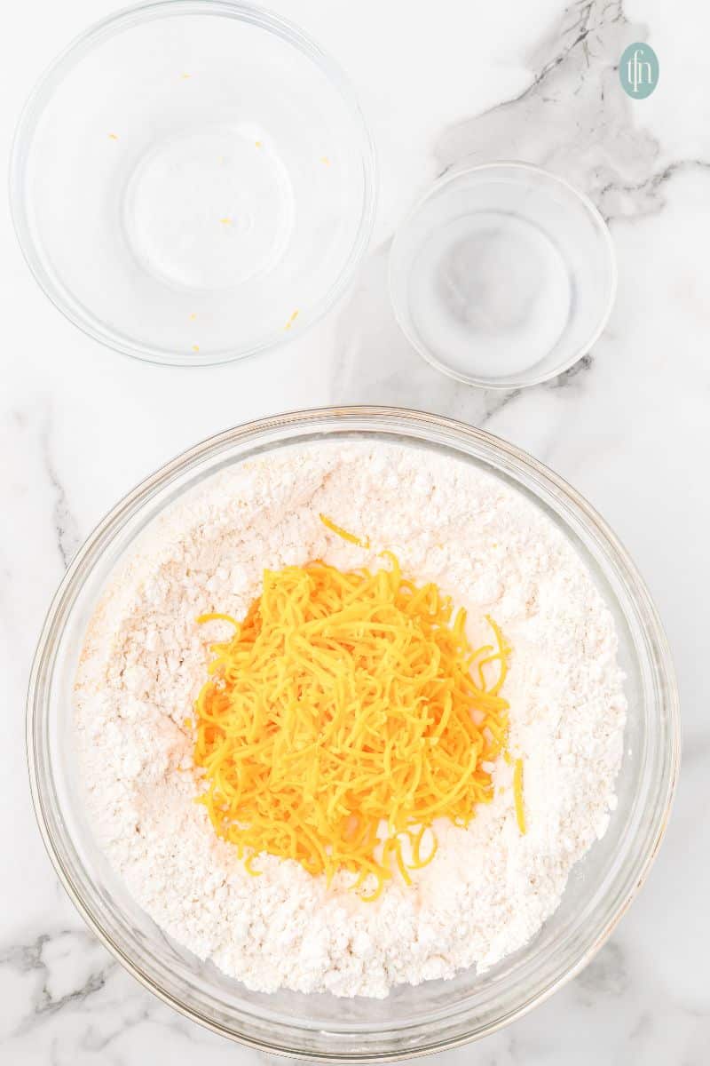 A bowl with dry ingredients and shredded cheese.