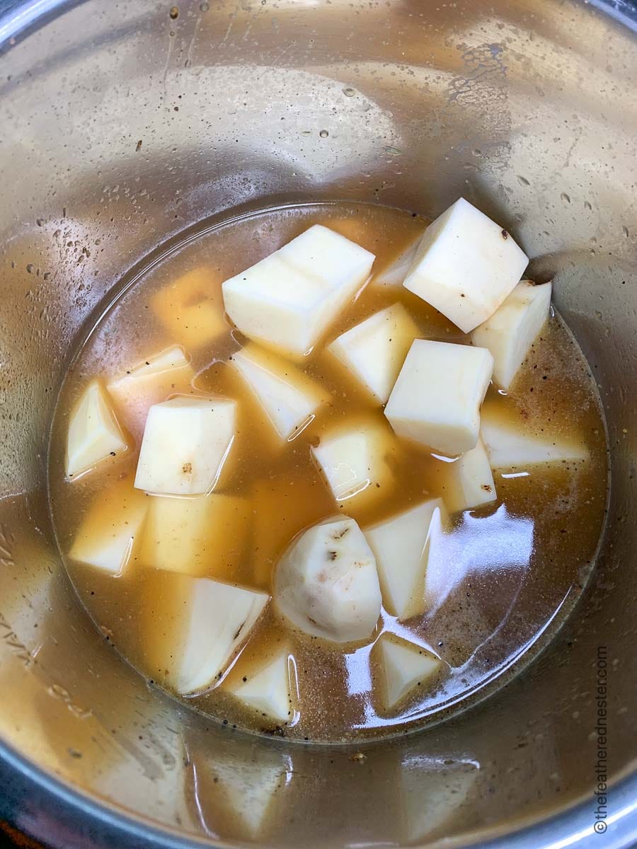 Peeled potatoes, cut into cubes, in a pressure cooker with broth.