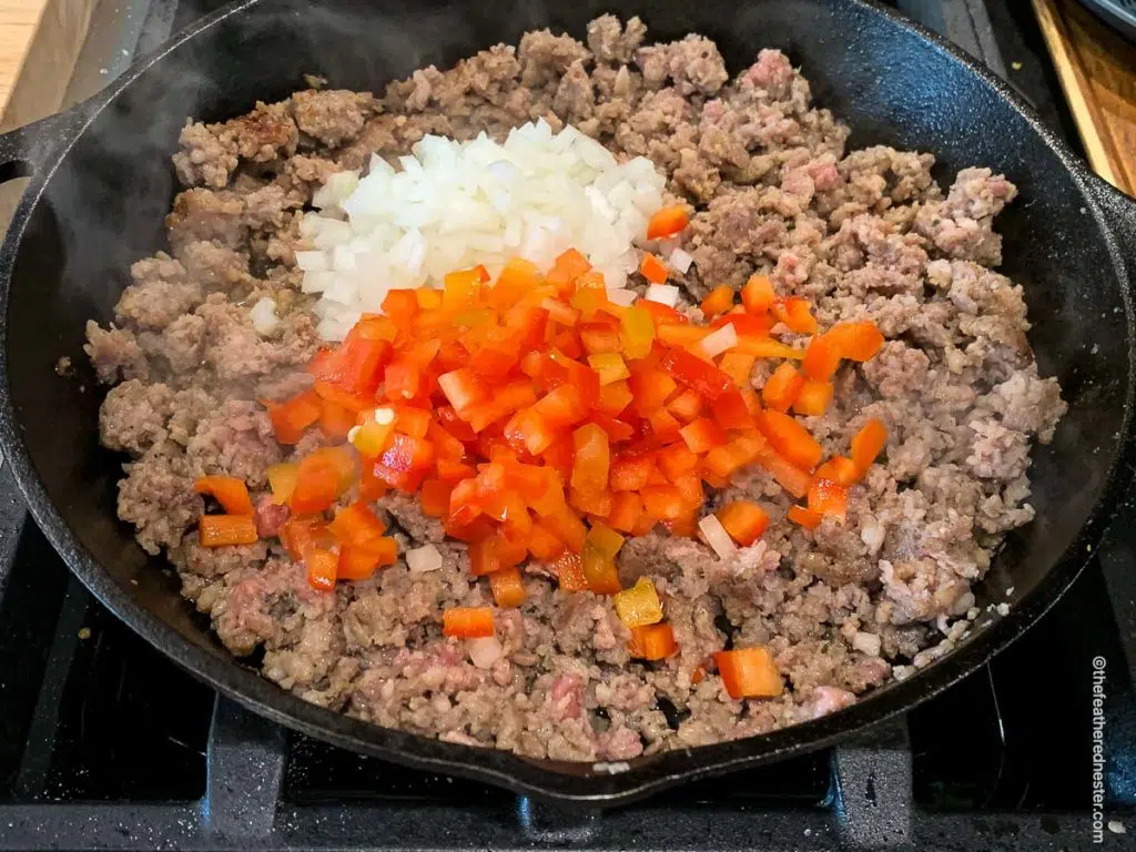 a skillet of sausage, bell pepper, and onion sautéing 