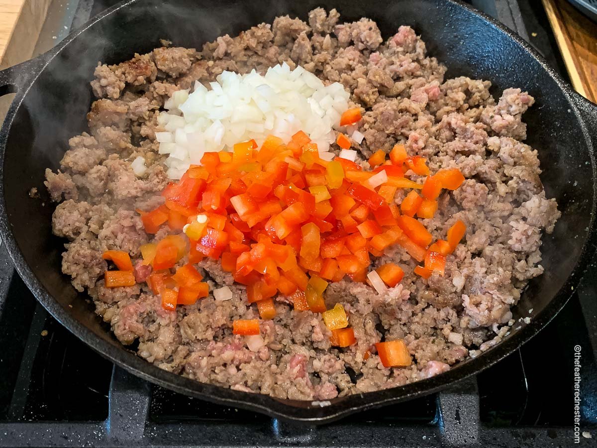 a skillet of sausage, bell pepper, and onion sautéing.