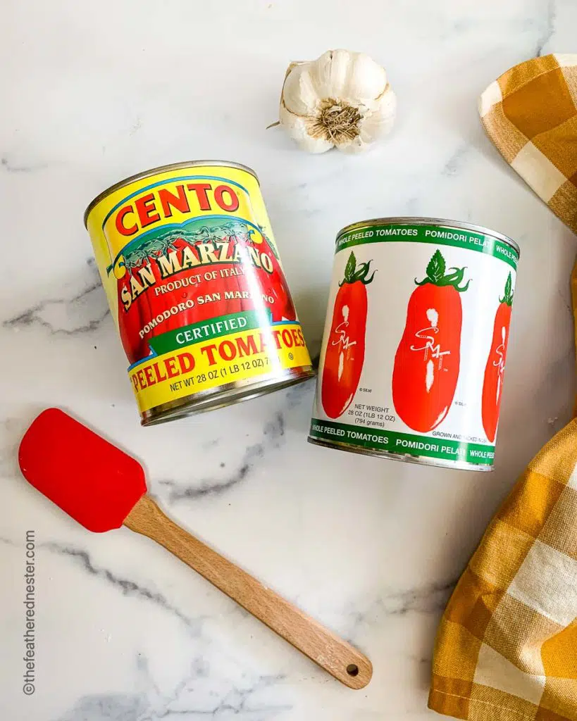 cans of Cento San Marzano tomatoes and Pomidori Pelati tomatoes with garlic and red spatula