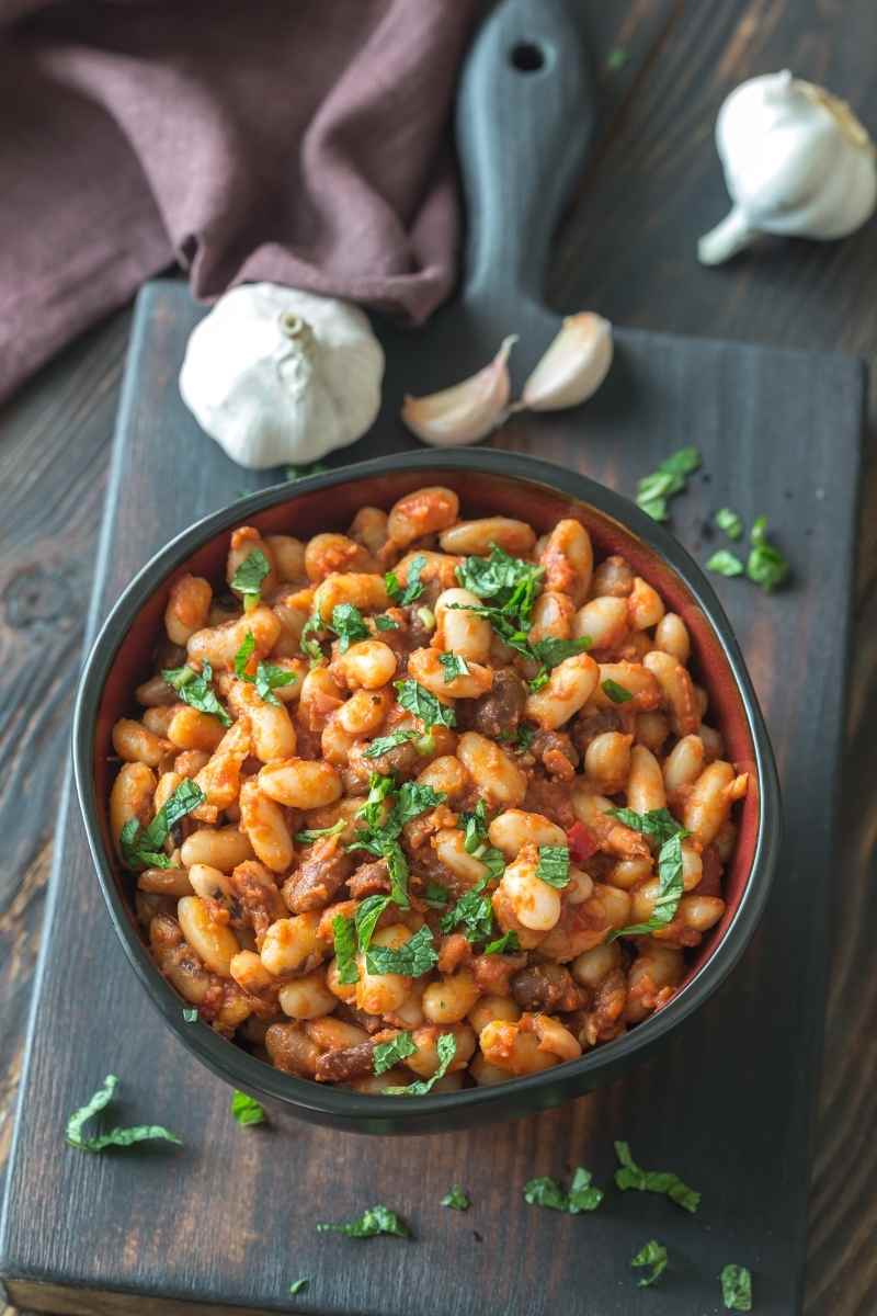 a bowl of calico beans on a wooden board