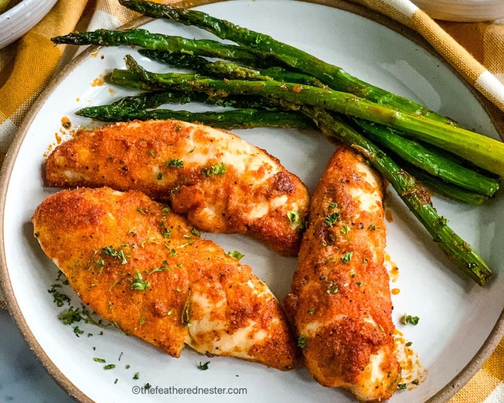 a plate with baked chicken tenders and asparagus.