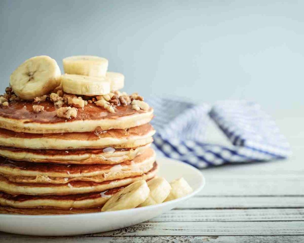 a stack of pancakes topped with sliced bananas