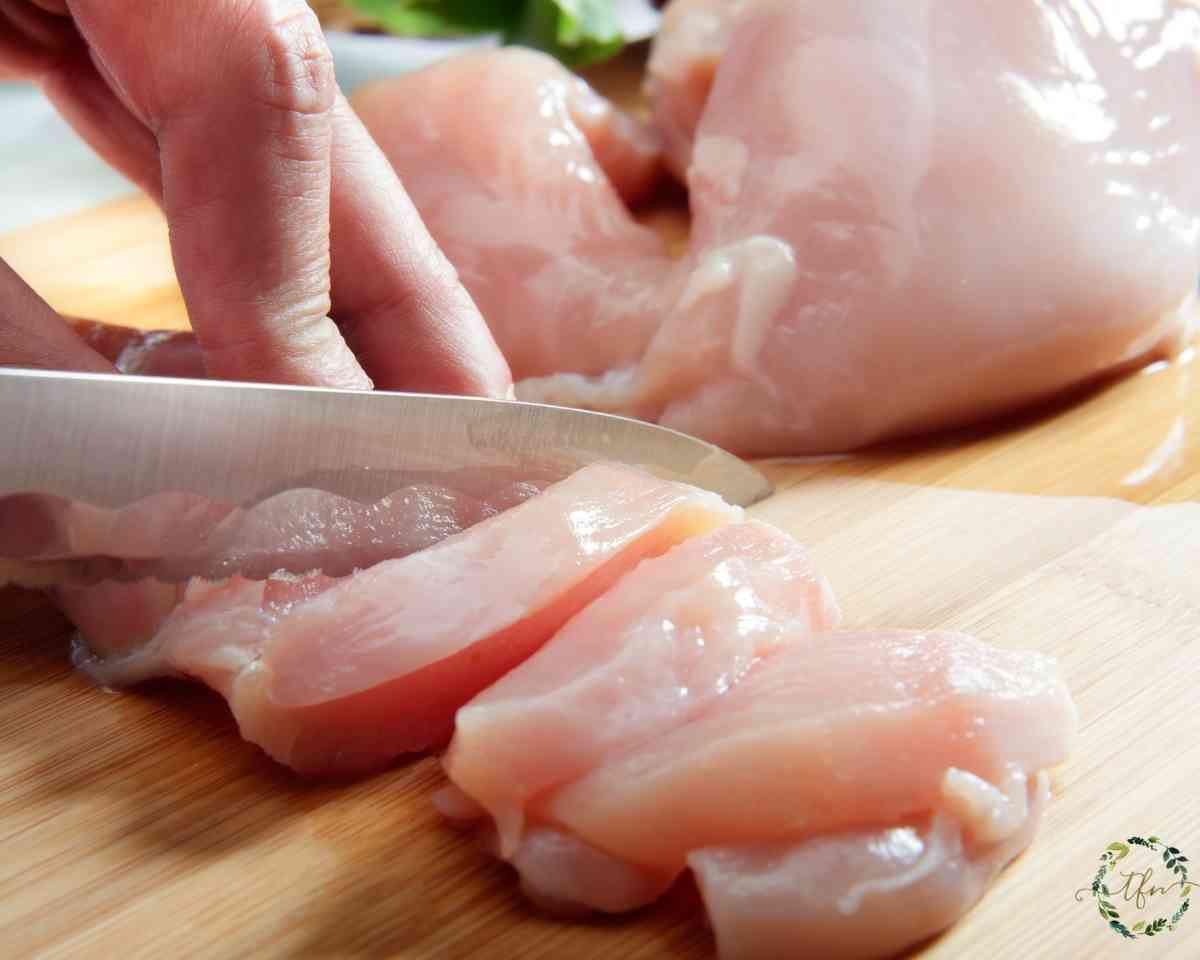 cutting chicken breast into chicken tenders strips.