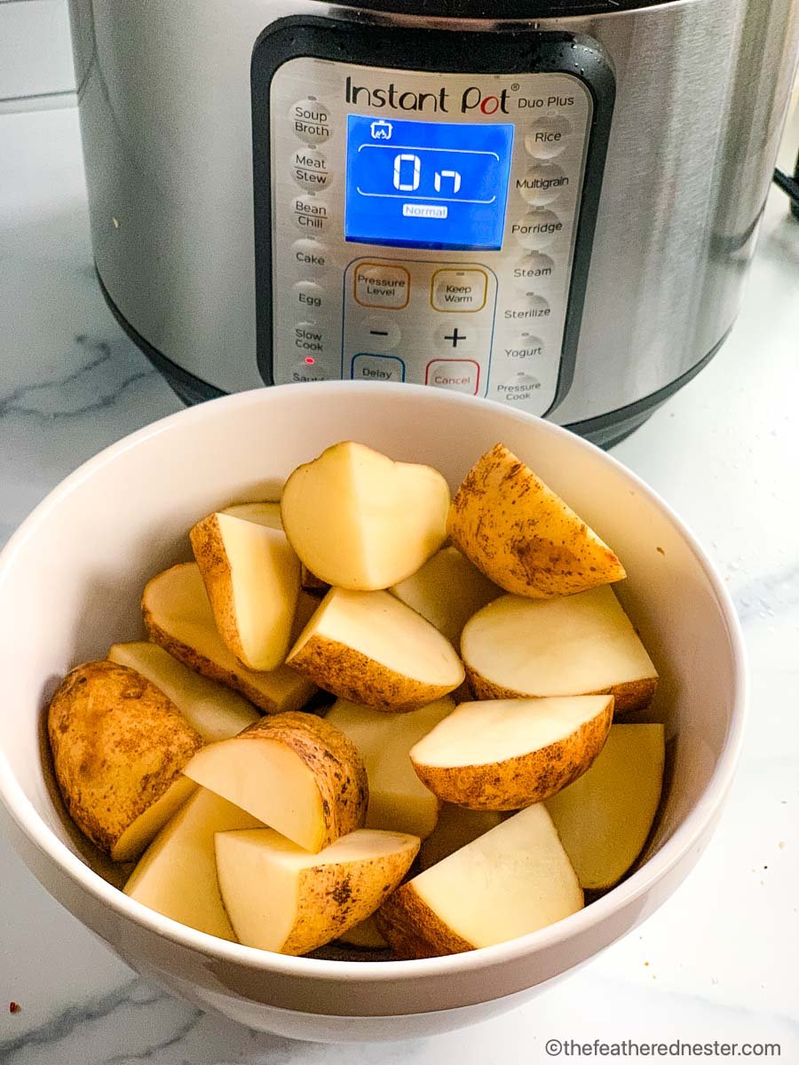 Cut potatoes in a bowl in front of an electric pressure cooker.