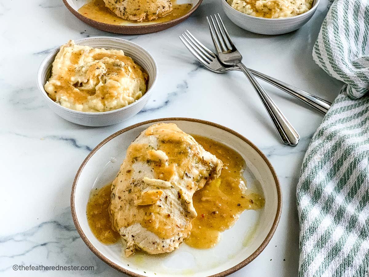 A plate of crock pot turkey tenderloin and a bowl of mashed potatoes with fork and dish towel