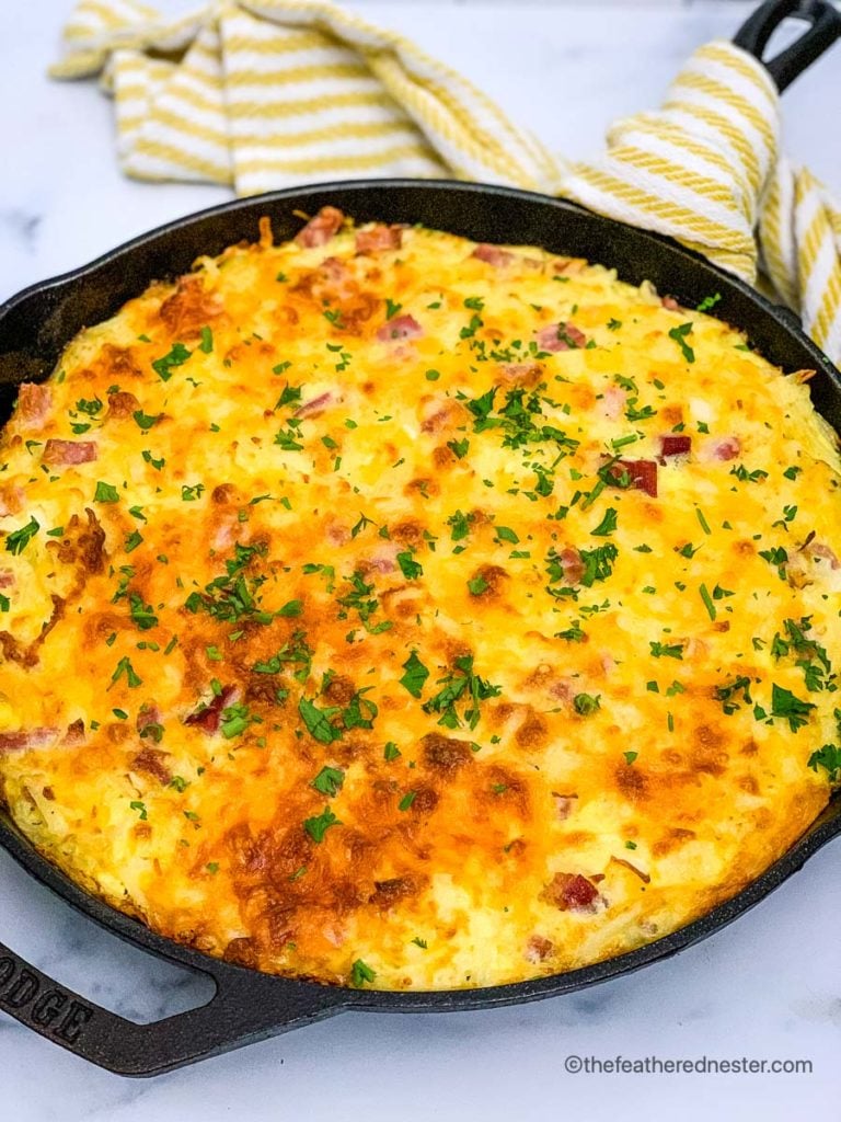a skillet of breakfast casserole with hash browns and ham baked and ready to serve