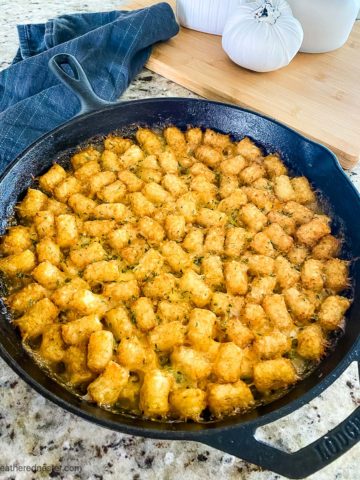 baked tater tot casserole in a cast iron skillet ready to serve