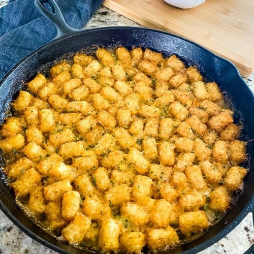 baked tater tot casserole in a cast iron skillet ready to serve.