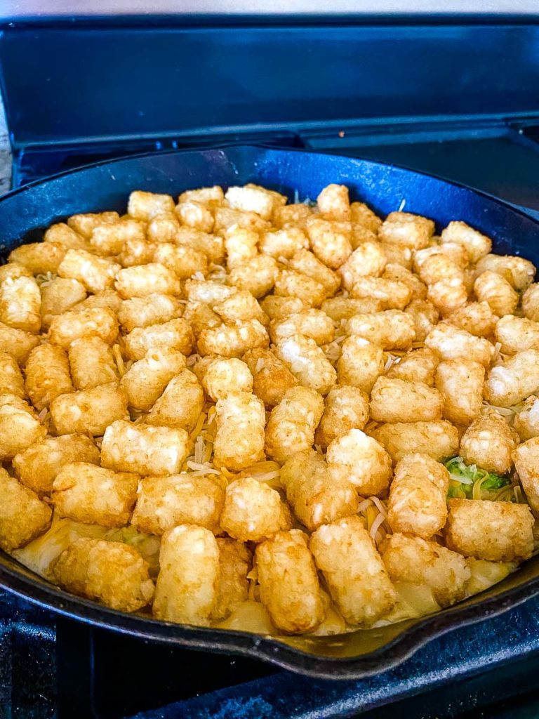 A skillet of unbaked chicken tater tot casserole.