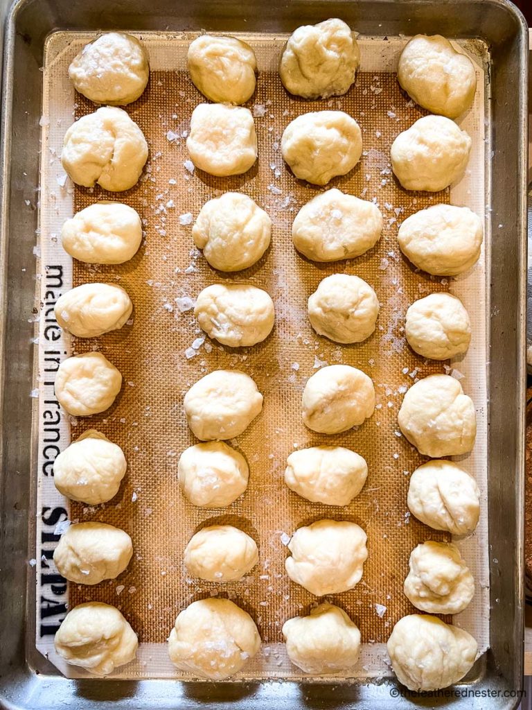 a baking sheet covered with a silicone baking sheet and dipped dough for pretzel balls