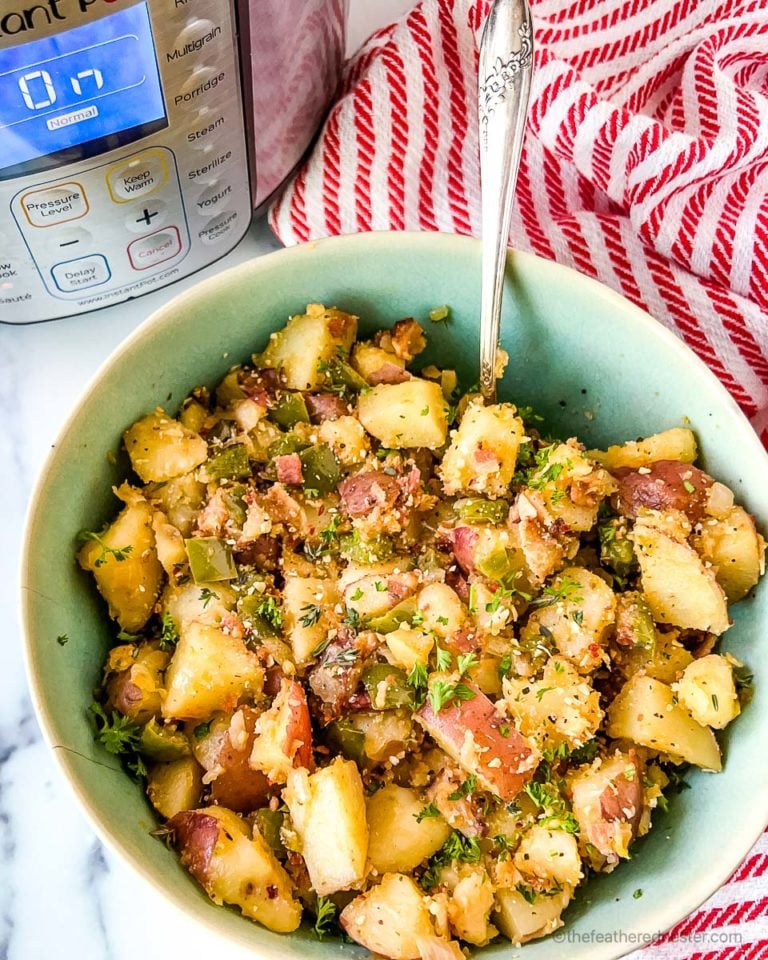 A green bowl of crispy breakfast potatoes with a serving spoon on top of a red and white striped napkin and an Instant Pot in the background