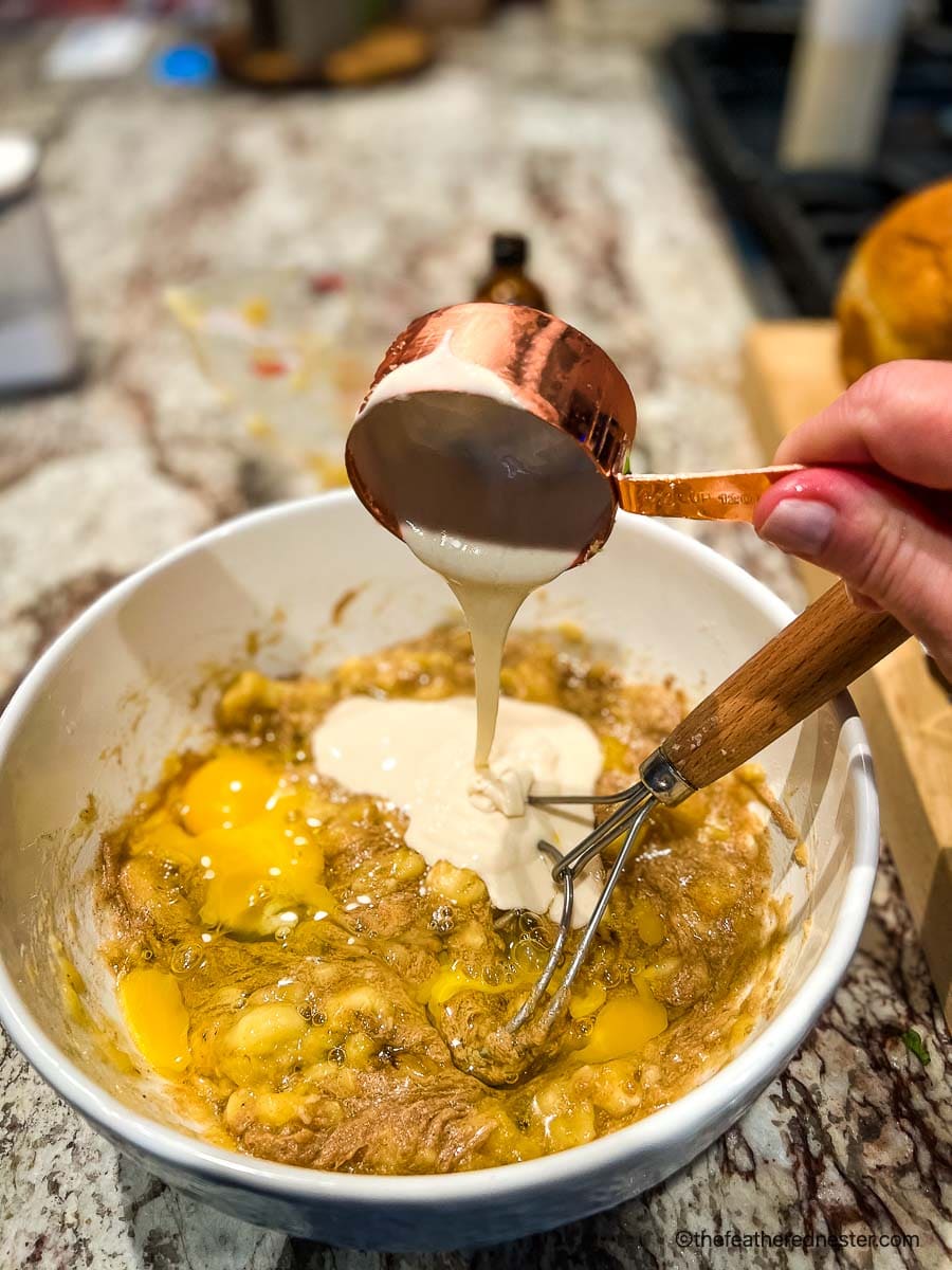 Pouring sourdough discard into banana bread batter.