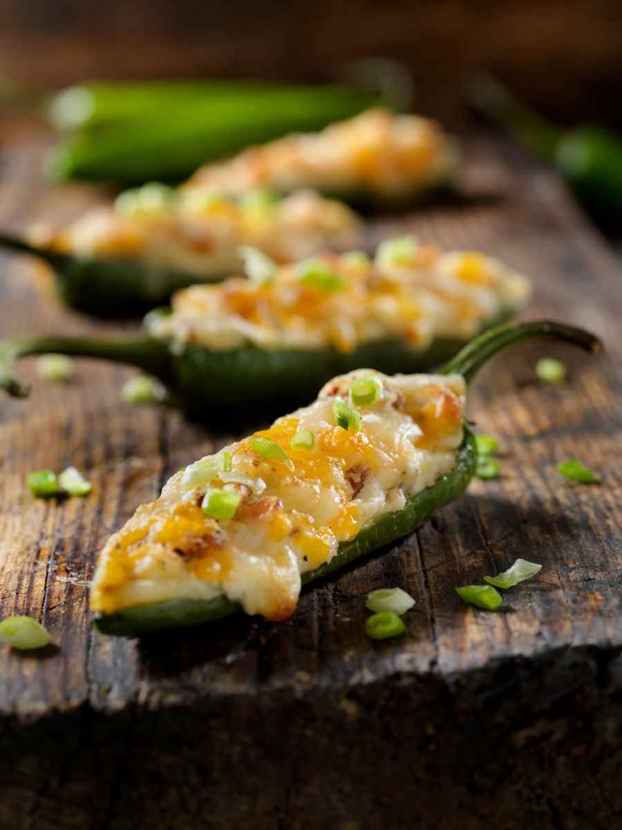 a board with freshly baked jalapeno poppers with cream cheese filling.