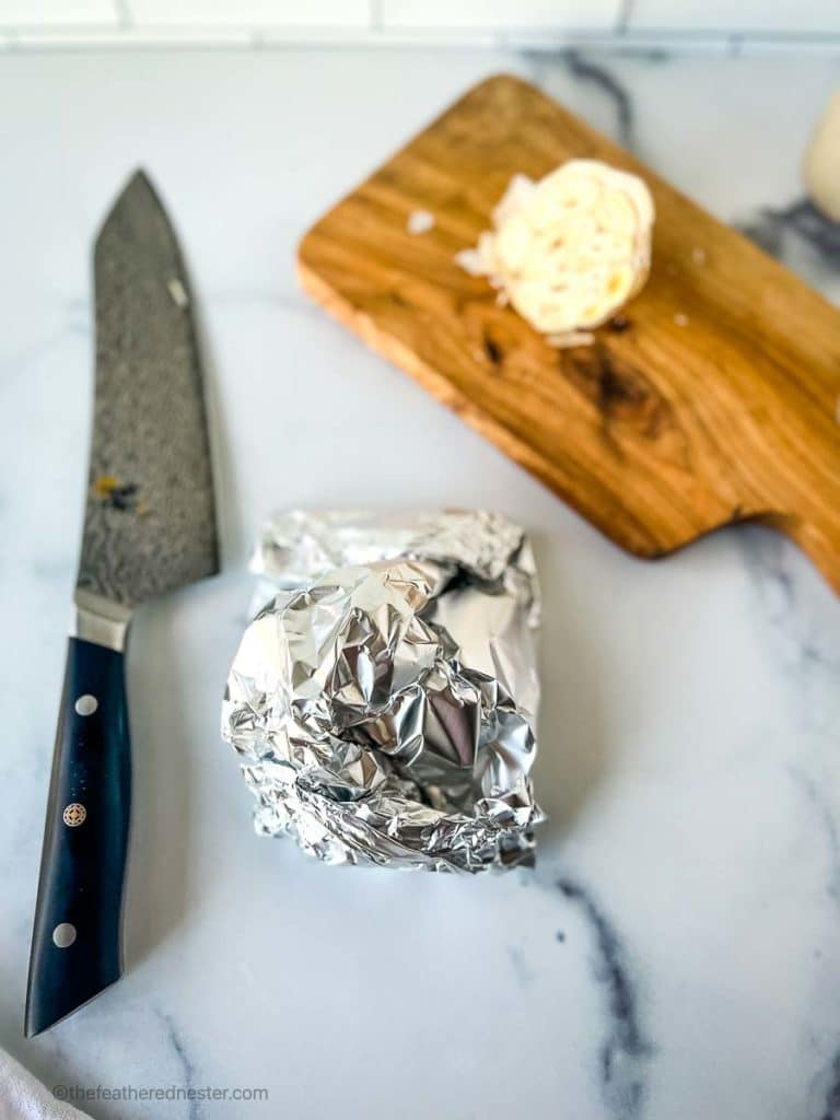 a bulb of garlic sealed in aluminum foil to roast in the oven