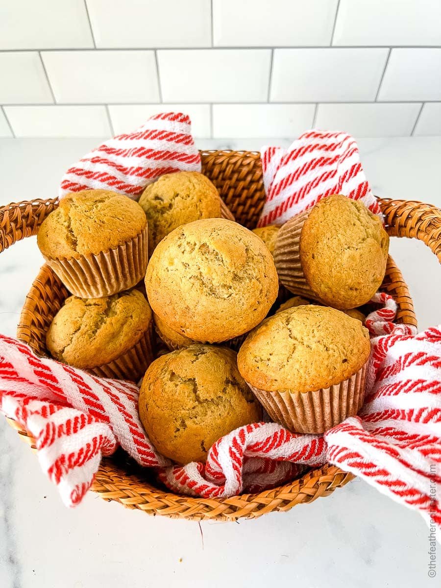 sourdough banana muffins in a wicker basket with a striped tea towel.