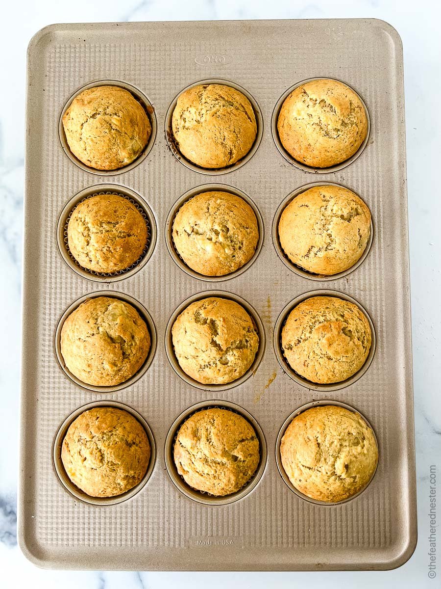 A muffin tin of freshly baked banana muffins made with sourdough.