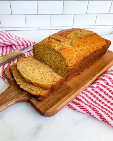 sliced banana bread recipe with self rising flour ready to serve from a wooden board with a red and white napkin