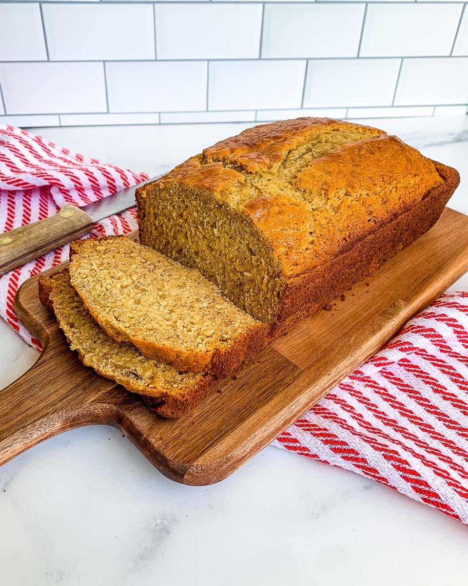 sliced banana bread recipe with self rising flour ready to serve from a wooden board with a red and white napkin
