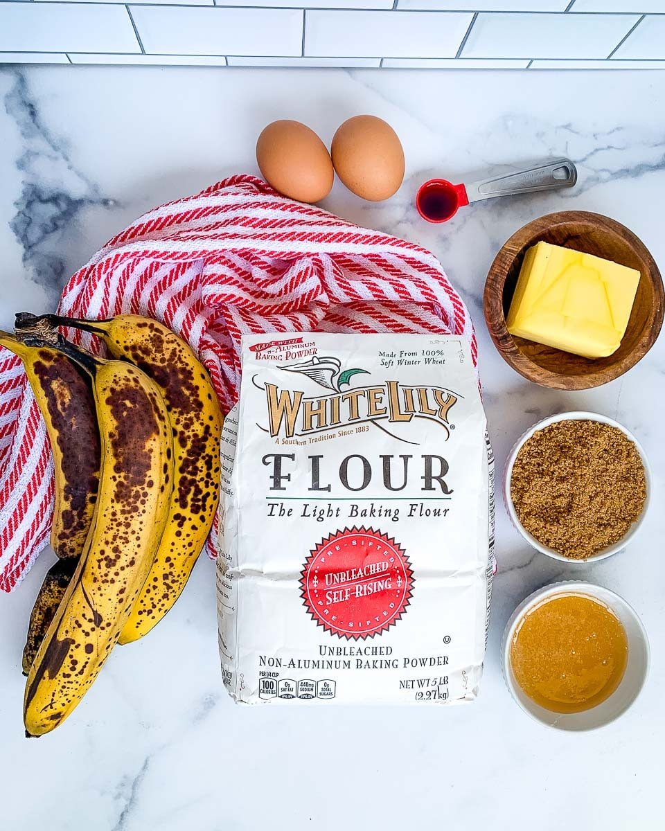 A bag of White Lilly brand self rising flour, bananas, butter, honey, two eggs, vanilla extract, brown sugar.