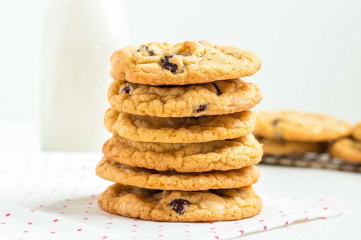 A stack of cookies with a bottle of milk in the background.