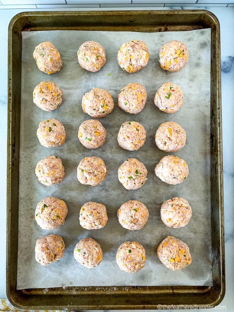 Meatball mixture rolled and arranged on a sheet pan, ready to bake in the oven