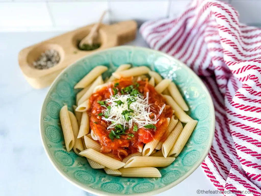 a green pasta bowl with penne al pomodoro - pasta with an Italian tomato sauce