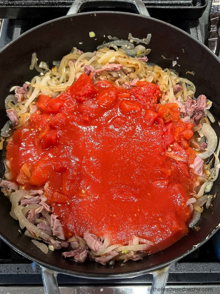 a cast iron skillet with penne al pomodoro sauce ready to simmer