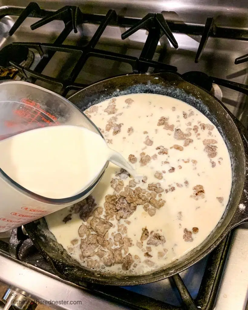 pouring milk on the cast iron skillet of turkey sausage gravy cooking