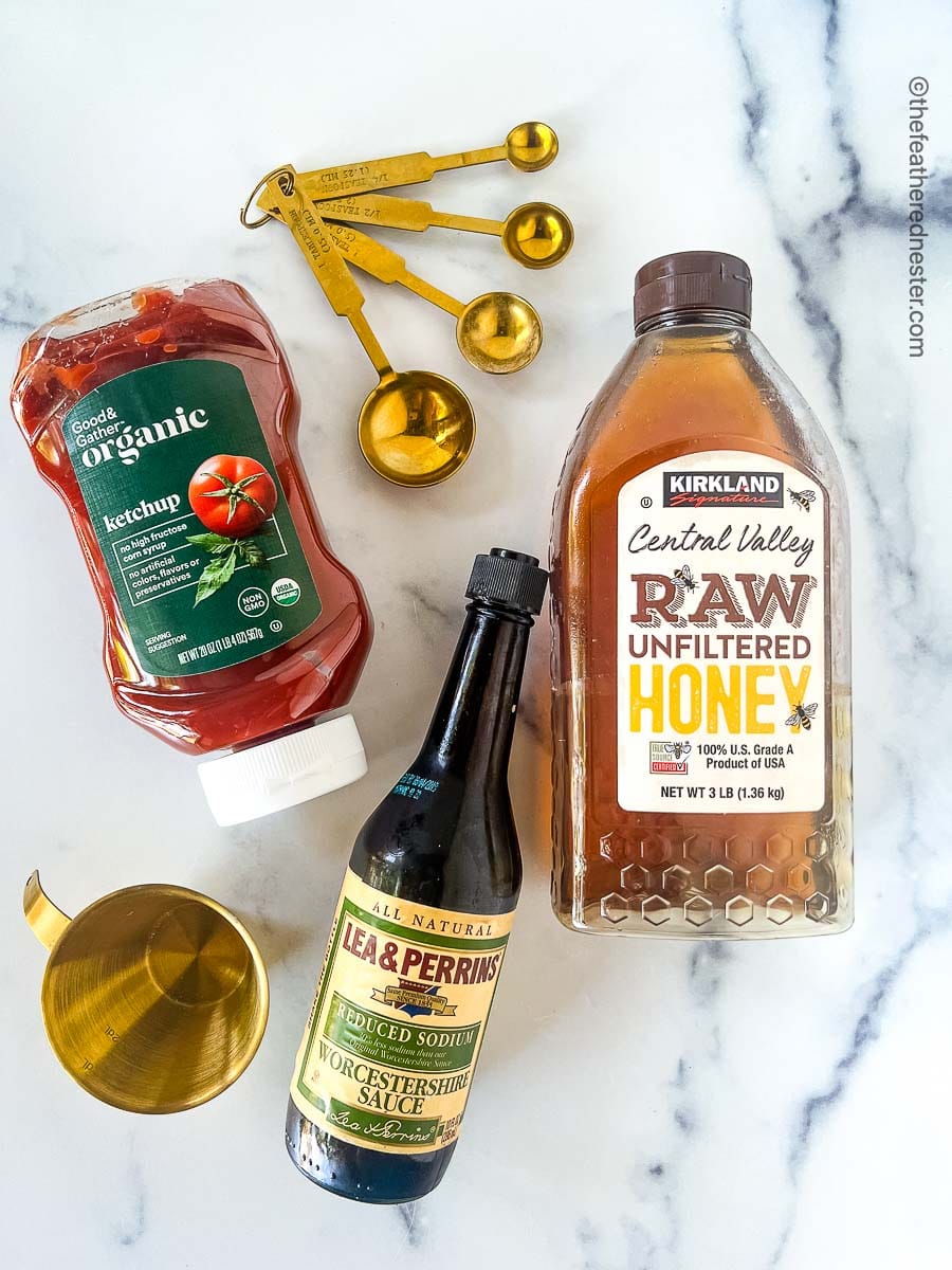 3 Ingredients for the BBQ Sauce, Ketchup, Raw Unfiltered Honey, and Worcestershire Sauce along with the measuring spoon and cup.