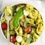 a white bowl of tortellini caprese salad with tomatoes